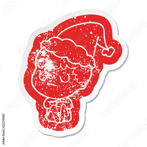 cartoon distressed sticker of a grumpy boy wearing santa hat