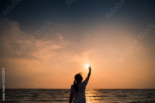 Silhouette Young Woman hands in Heart symbol shaped Lifestyle and Feelings concept with sunset light nature on the beach background.