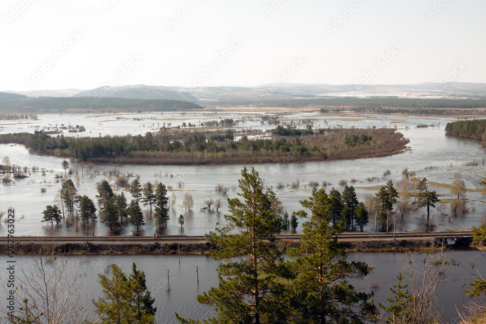Fototapeta premium Overflowing river, flooded fields and forest