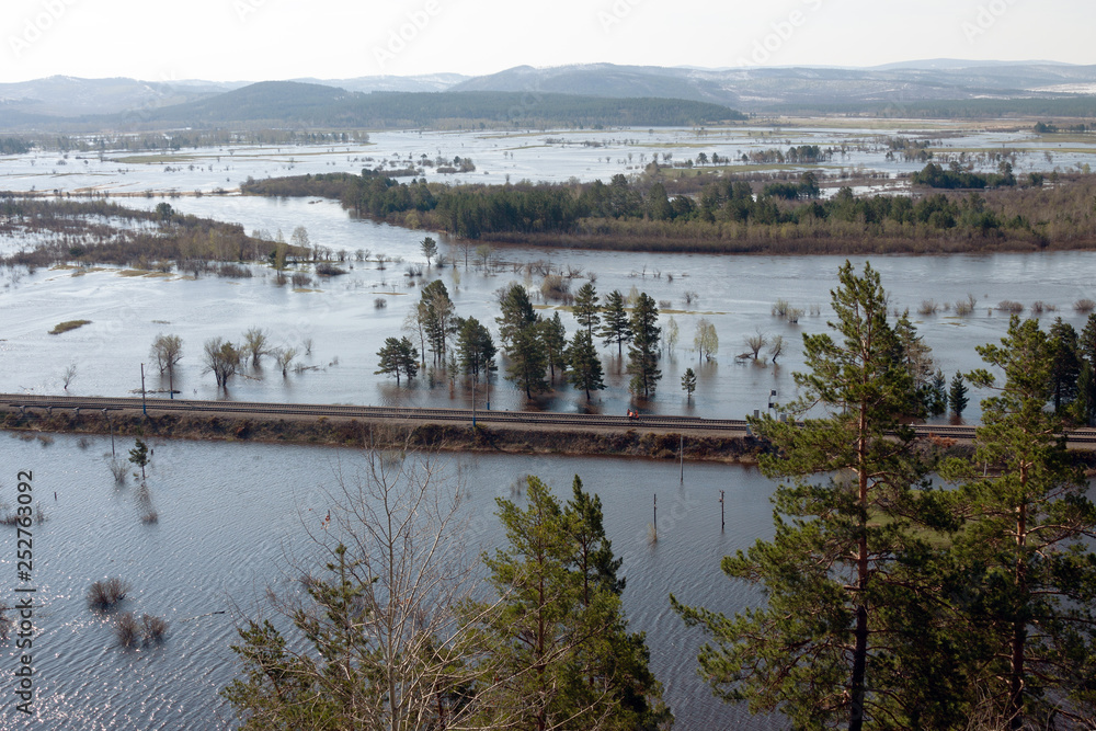 Naklejka premium Overflowing river, flooded fields and forest