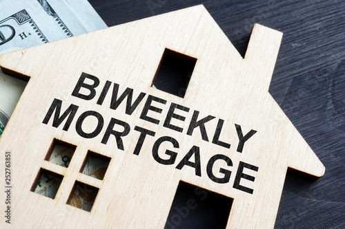 Biweekly mortgage. Wooden model of house and money.