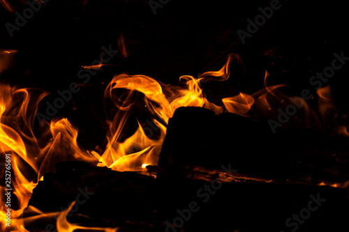 Flames shaping over dark firewood being burned