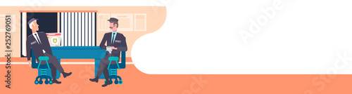 two male security guard workers discussing men in uniform sitting at workplace desk with laptop screen surveillance room interior full length flat horizontal banner