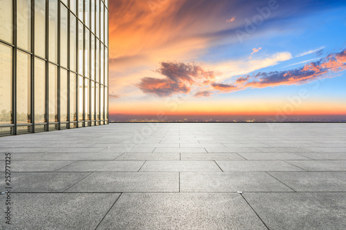 Empty square floor and modern city skyline with buildings at sunset