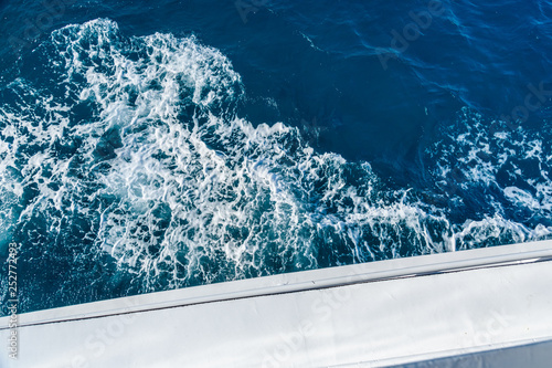 Wave trace with white foam on a water surface behind of fast moving yacht