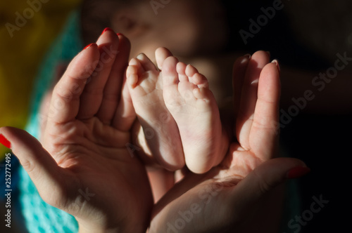 Baby legs in mom's hands close up