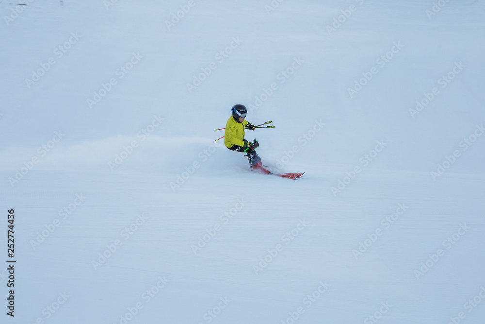 Skier skiing downhill on the snowy slope in the early morning