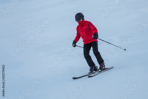 Skier skiing downhill on the snowy slope in the early morning