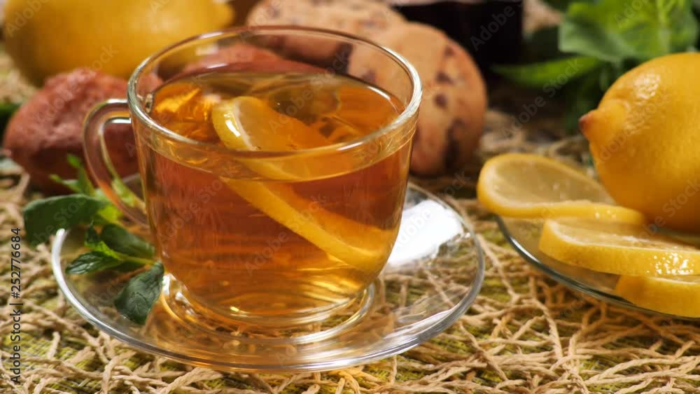 Hand put a slice of lemon in a Cup of tea. Tea with mint, lemon and cookies Hand put a slice of lemon in a Cup of tea. Tea with mint, lemon and cookies