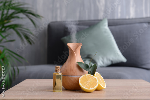 Aroma oil diffuser and citrus fruit on table in room photo