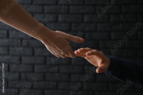 Woman giving hand to depressed man against dark background. Suicide prevention concept