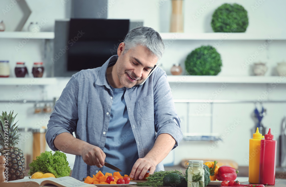 Mature man cooking dinner while talking by phone at home Mature man cooking dinner while talking by phone at home