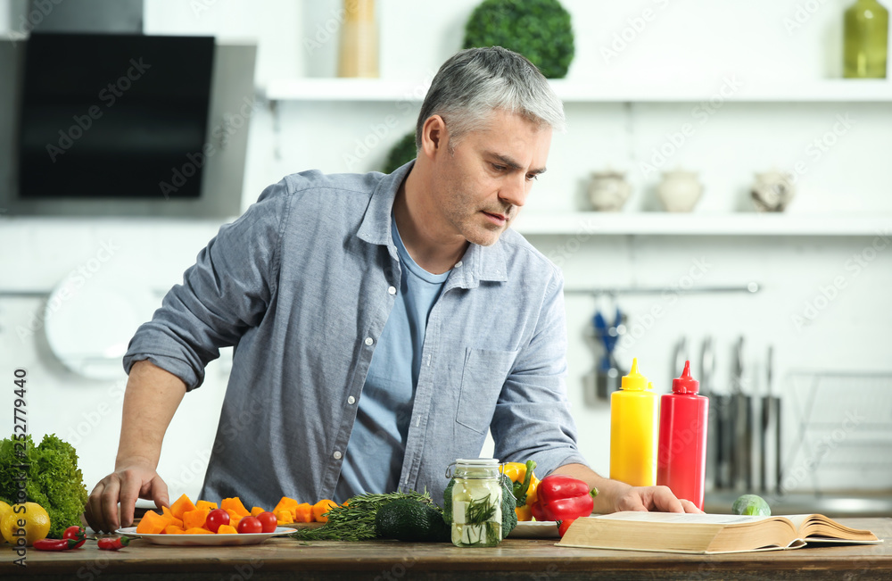 Fototapeta premium Mature man cooking dinner at home