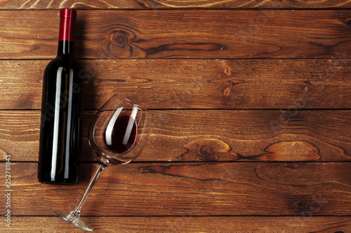 Red wine bottle, wine glass and corkscrew on wooden table background