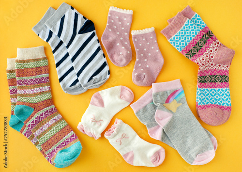 Socks on a yellow background. View from above. Socks of different sizes and colors on a bright yellow background. Clothing in the form of socks for adults and children.