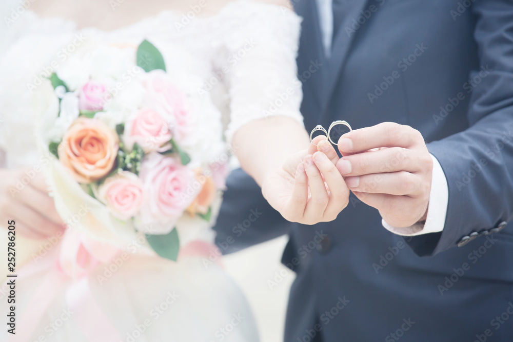 Close up Groom hand and bride. picture of man and woman newly wed couple hands with wedding rings and holding Bouquet of beautiful a rose flower. lover Wedding ceremony. Close up Groom hand and bride. picture of man and woman newly wed couple hands with wedding rings and holding Bouquet of beautiful a rose flower. lover Wedding ceremony.