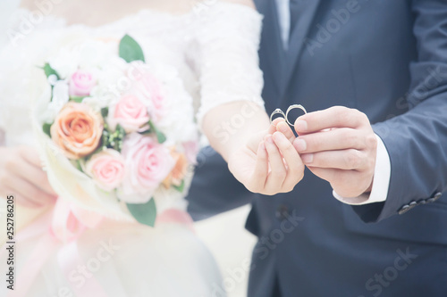 Close up Groom hand and bride. picture of man and woman newly wed couple hands with wedding rings and holding Bouquet of beautiful a rose flower. lover Wedding ceremony.