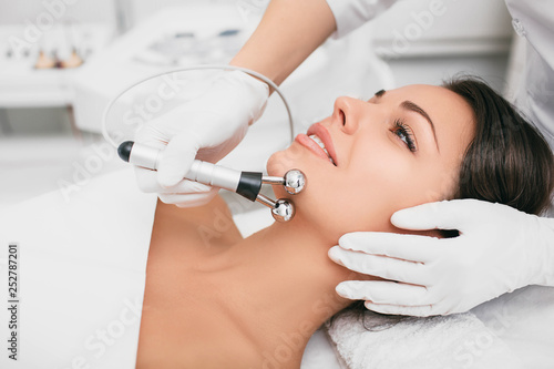 Beautiful woman receiving facial microcurrent procedure for lifting face. Facial rejuvenation and facelift with microcurrent therapy