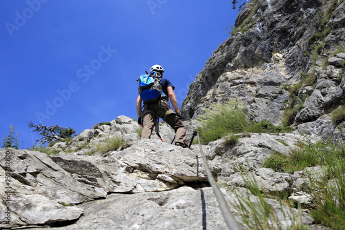 Mann klettert am Klettersteig in den Alpen
