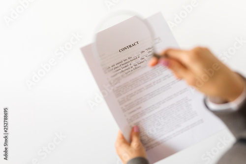 Person reading contract with magnifying glass
