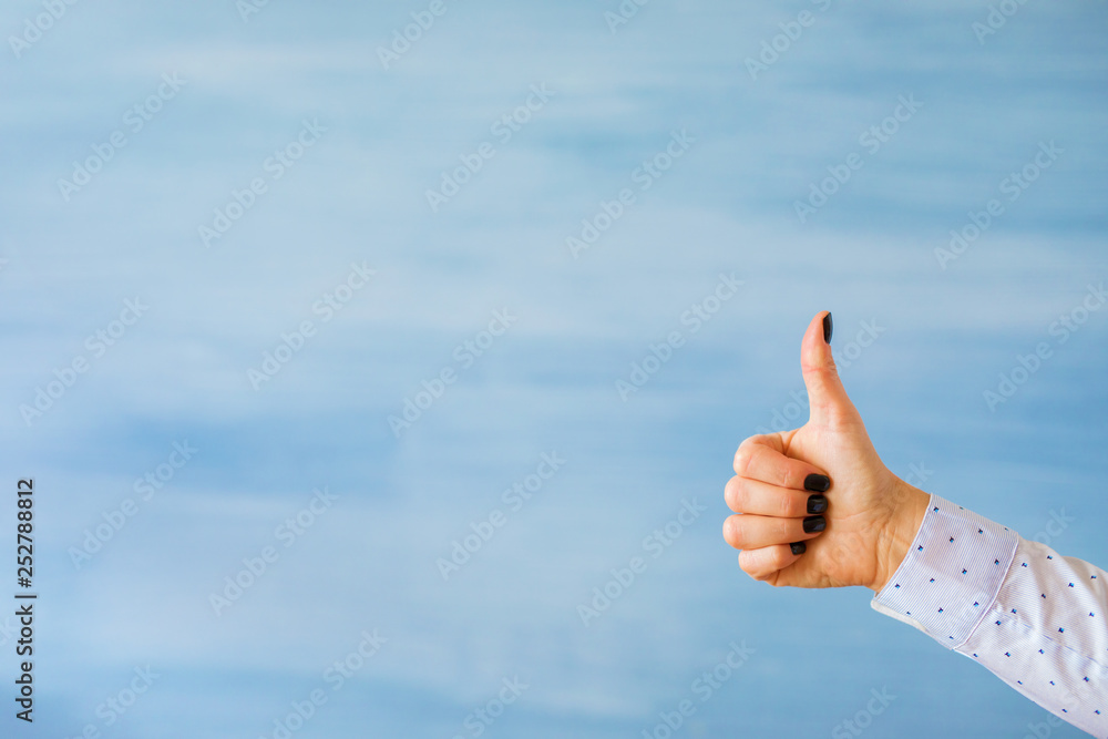 Person showing thumbs up hand gesture on empty blue background Person showing thumbs up hand gesture on empty blue background