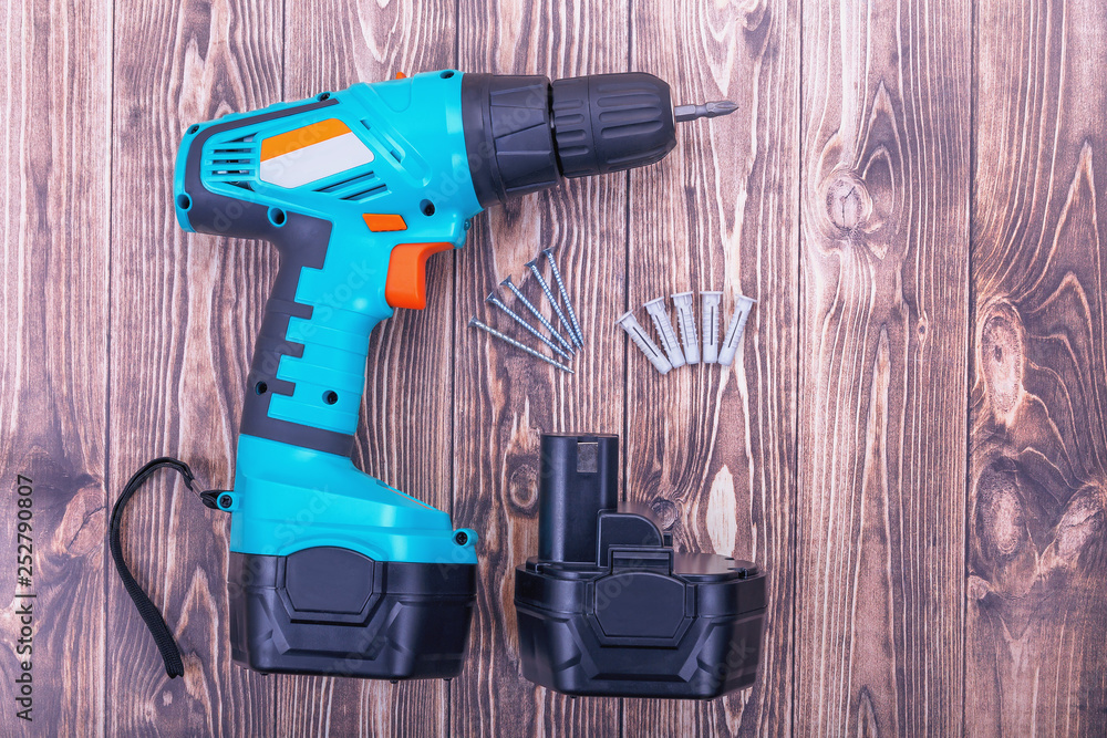modern cordless screwdriver and screws on wooden background modern cordless screwdriver and screws on wooden background