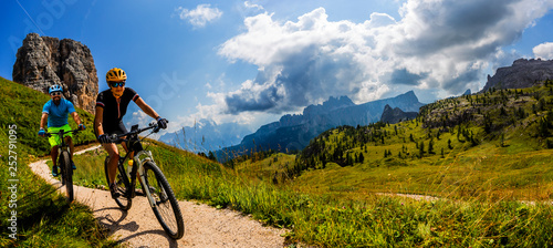 Cycling woman and man riding on bikes in Dolomites mountains landscape. Couple cycling MTB enduro trail track. Outdoor sport activity. © Gorilla