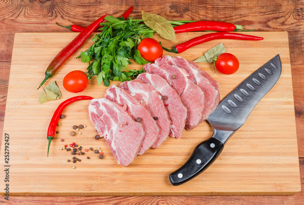 Uncooked steaks of pork neck on cutting board with knife Uncooked steaks of pork neck on cutting board with knife