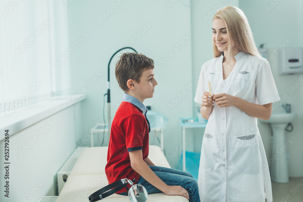 Woman ENT doctor examines boy's throat. Children's diseases, medical examination. Woman ENT doctor examines boy's throat. Children's diseases, medical examination.