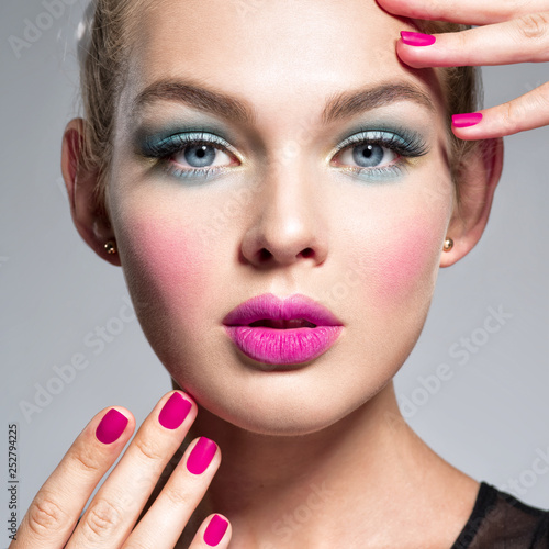 Beautiful woman  with blue makeup of eyes and pink nails.