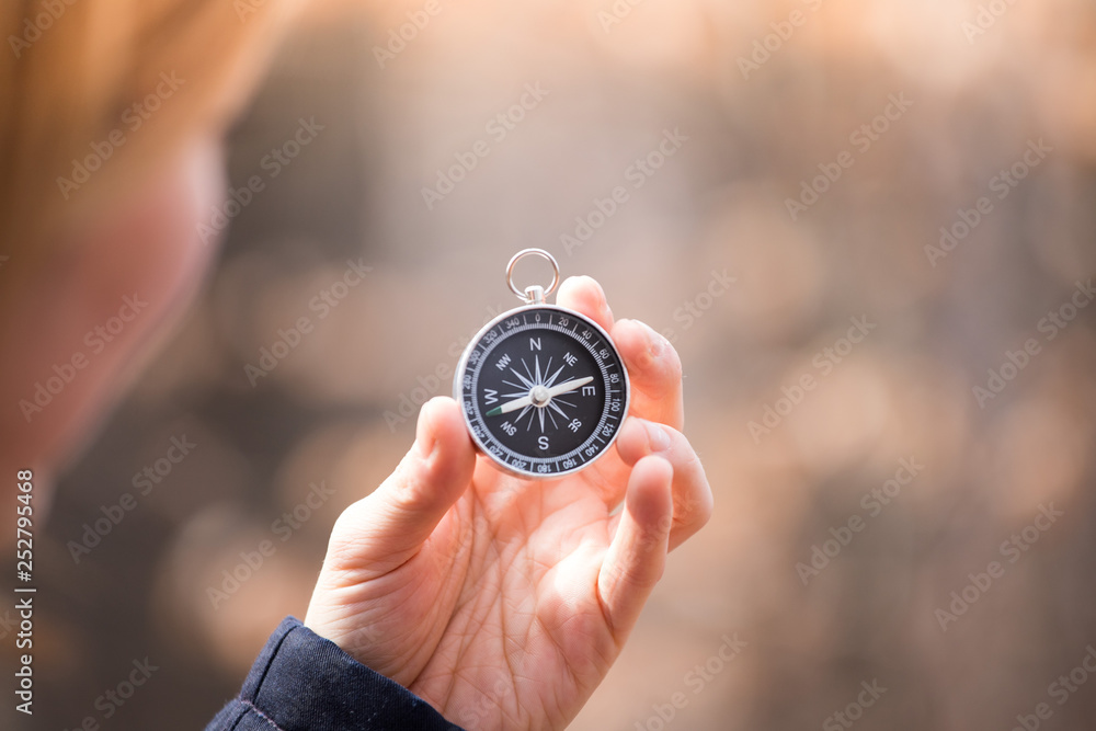 Compass holding in the hand of a girl, outdoor adventure, blurry face