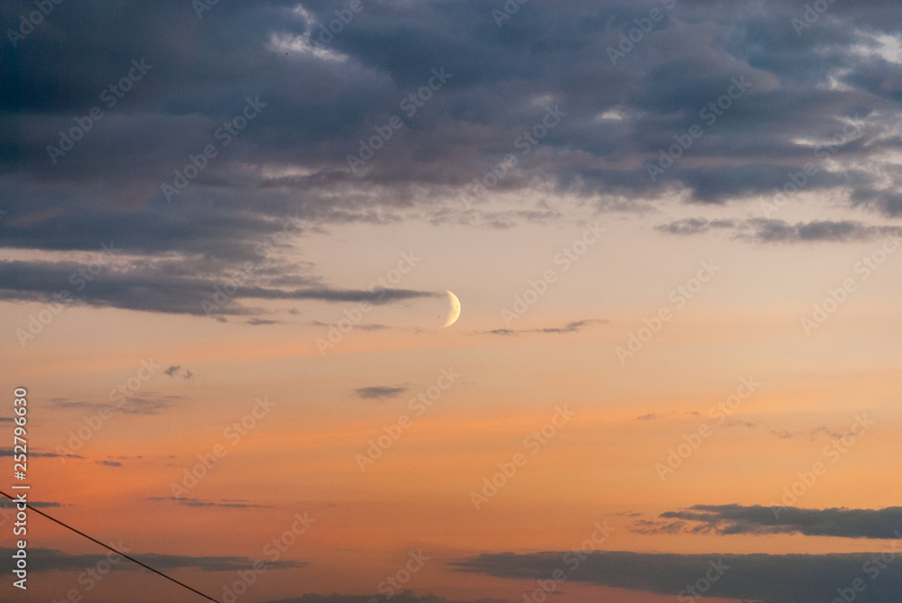 Moon rise in the sunset sky amidst the clouds