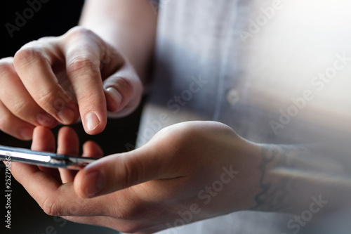 Male tattoo hands are typing in the phone