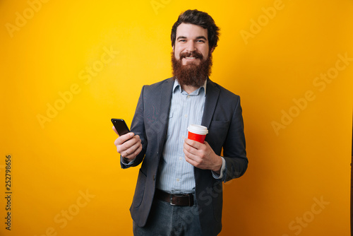 Happy and friendly young attractive Businessman use a Smart phone and holding morning coffee. Social communicate technology in business concept.