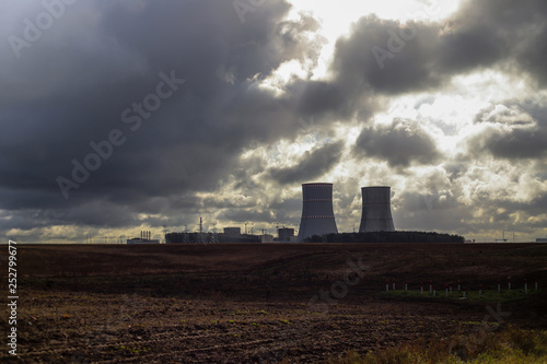 nuclear power plant on the background of a plowed field and overcast sky, distance shot