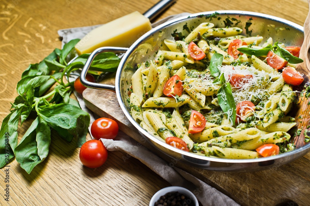 Penne pasta with spinach, cherry tomatoes and Basil. Wooden background, side view