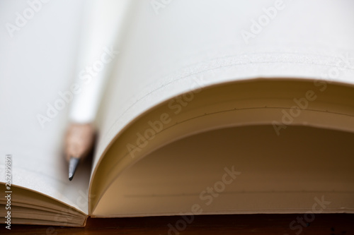 A white pencil on white notebook on wooden table background, Close up & Macro shot, Selective focus, Stationery concept