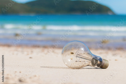 old light bulb onthe beach with blue ocean.