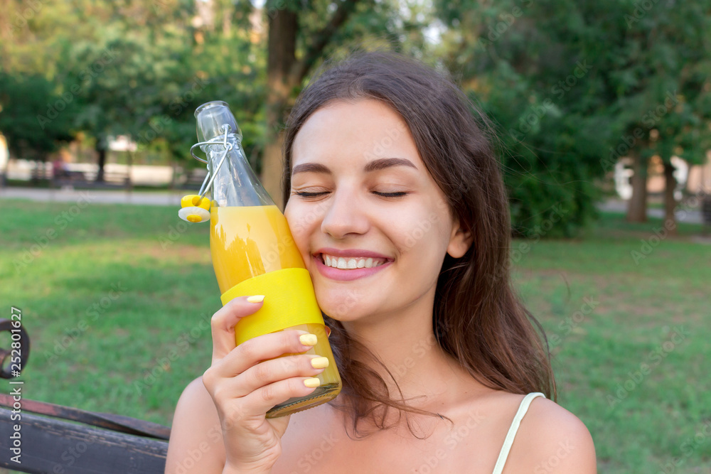 Young beautiful woman tries to refresh with a cold bootle of juice in a hot summer day Young beautiful woman tries to refresh with a cold bootle of juice in a hot summer day