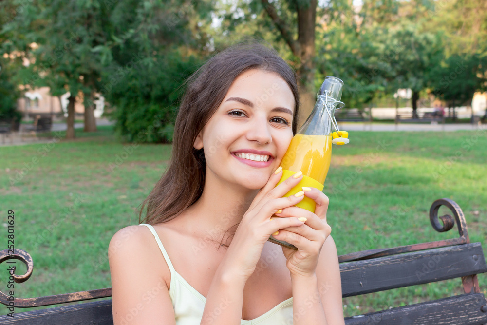 Young beautiful woman tries to refresh with a cold bootle of juice in a hot summer day Young beautiful woman tries to refresh with a cold bootle of juice in a hot summer day