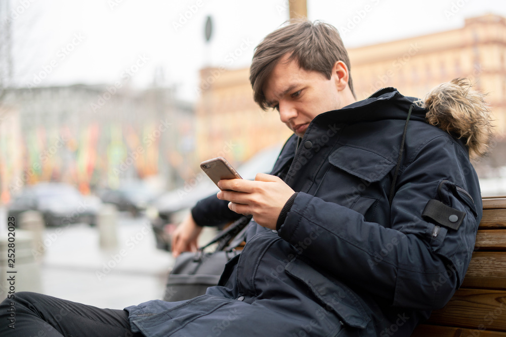 person use phone in the street and sit on bench b