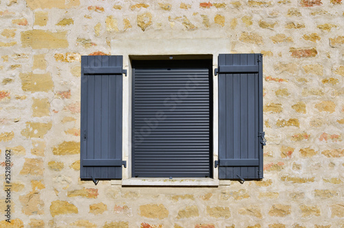 Fenêtres à volets gris sur mur de vieilles pierres