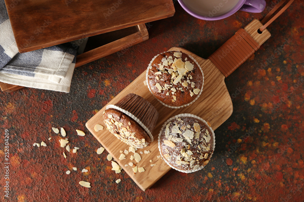 Board with tasty almond muffins on color table Board with tasty almond muffins on color table