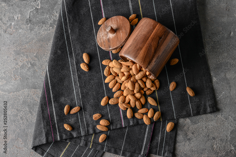 Fototapeta premium Wooden jar with tasty almonds on grey table