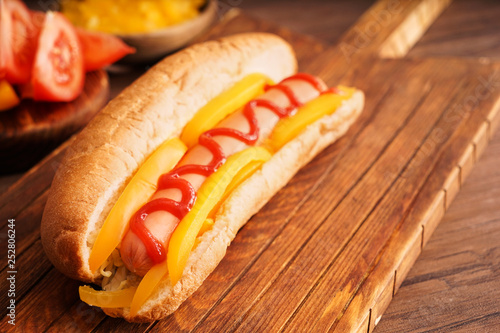 Tasty hot dog on wooden board