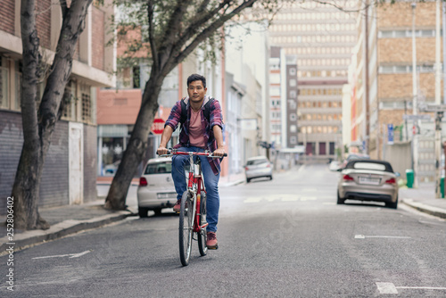 Young Asian man riding his bike on a city street © mavoimages
