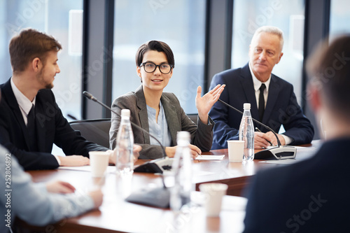 Bild auf Leinwand Portrait of young businesswoman speaking to microphone during group discussion i