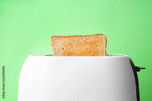 Slice of bread with toaster on color background