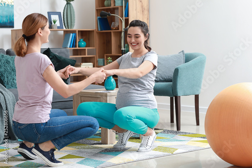 Doula and pregnant woman doing exercises at home