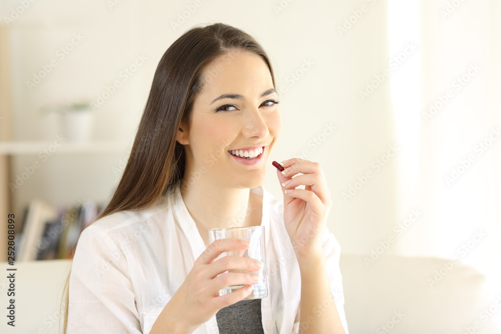 Happy woman taking painkiller capsule at home Happy woman taking painkiller capsule at home